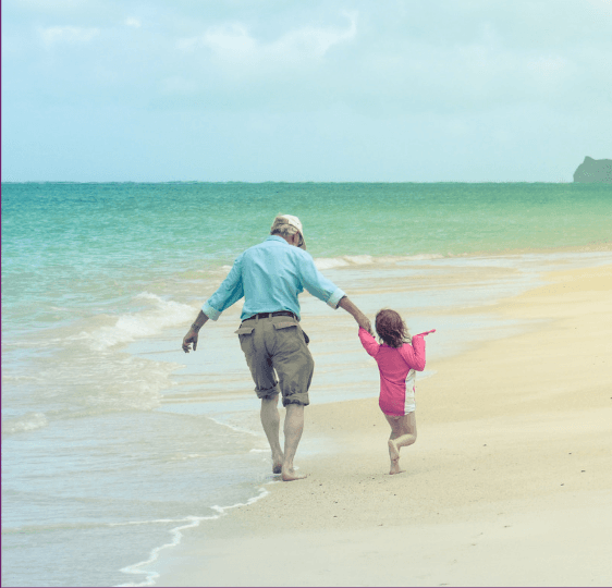 Grandad and toddler playing on the beach